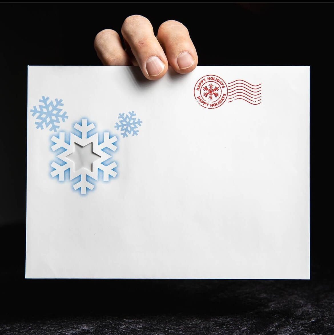hand holding an envelope with snowflakes on it
