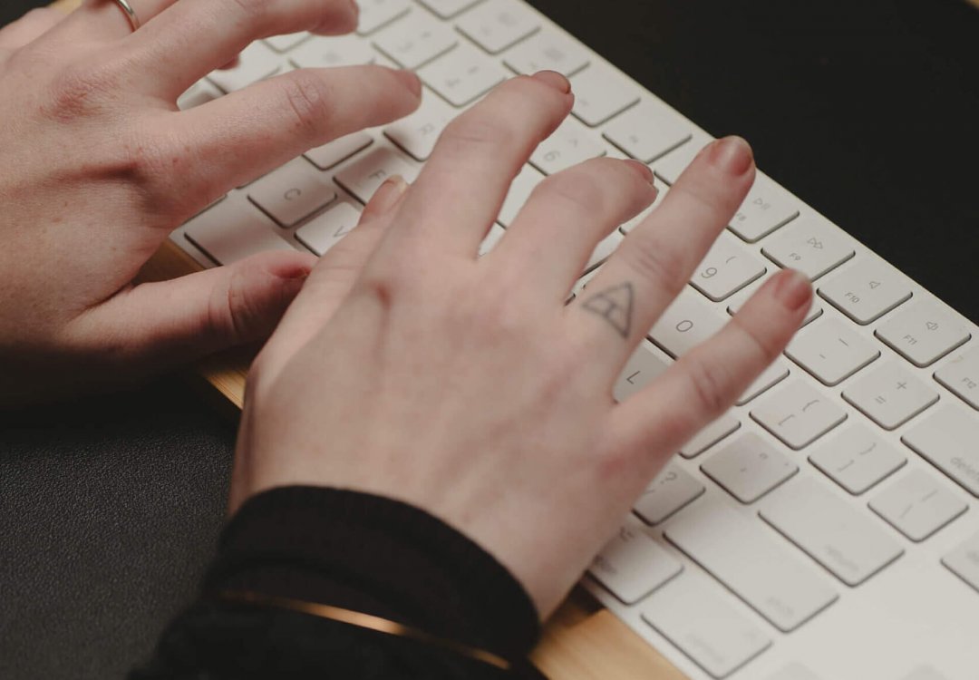 Hands typing on a mac keyboard